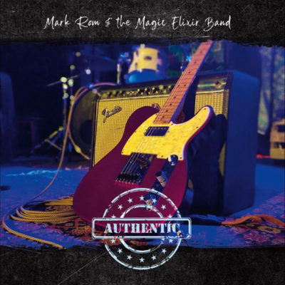 Electric Guitar leaning against amp, drums in background, text: Mark Rom & the Magic Elixir Band